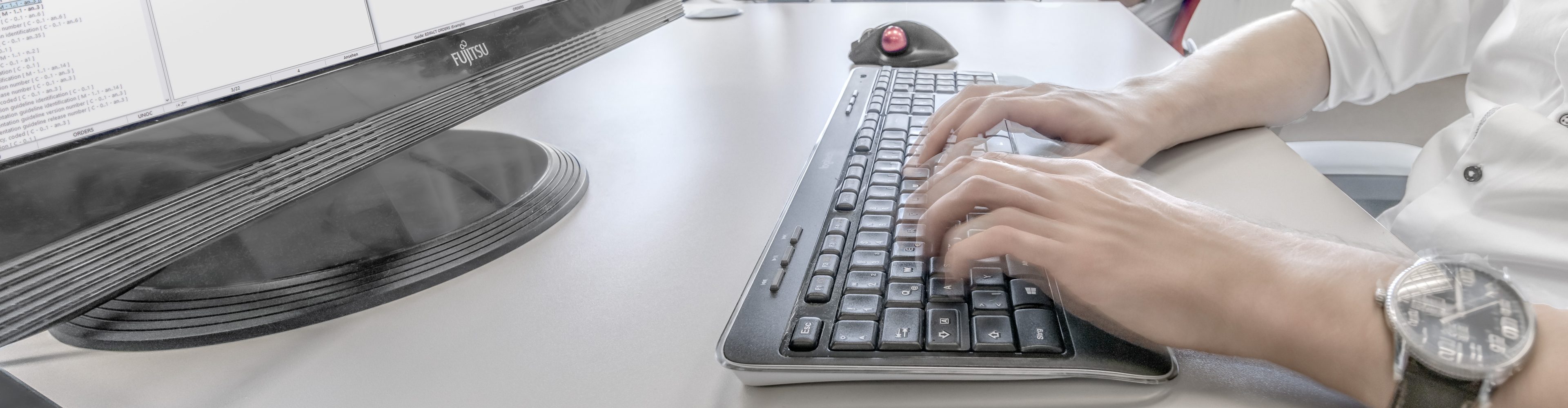 Employee typing on a keyboard with a large wristwatch on his left wrist