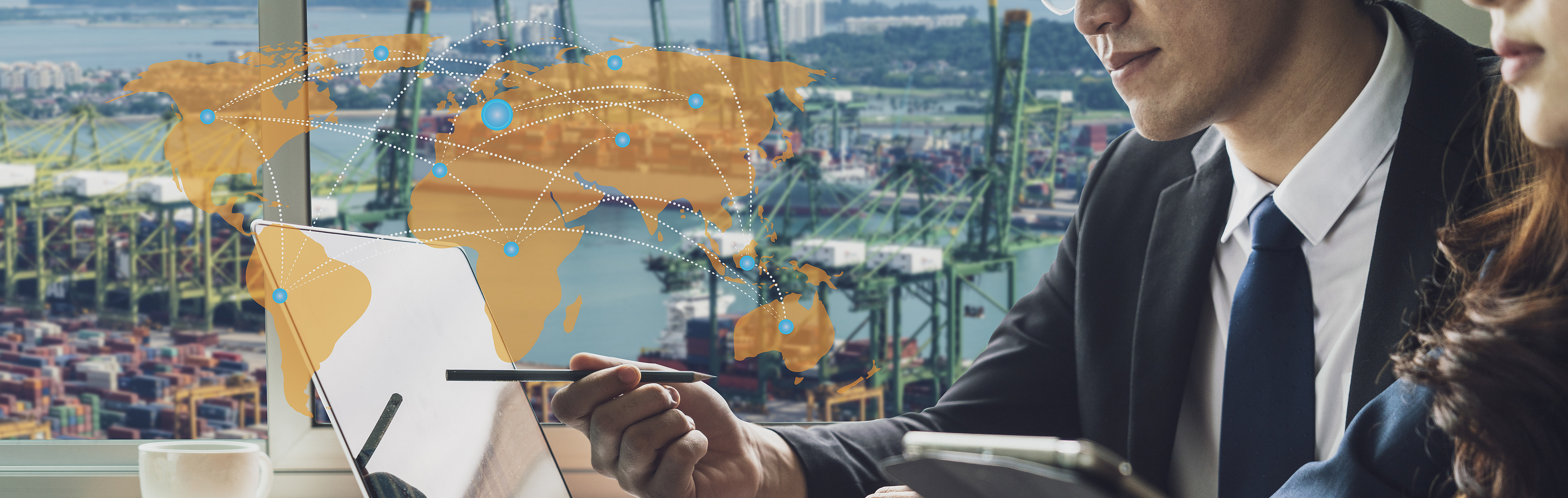 In the background of the picture you can see several harbour basins with various loading cranes, while in the foreground a woman and a man are sitting in front of a screen at a meeting. Superimposed on the image is an orange world map with dotted lines connecting places all over the world.