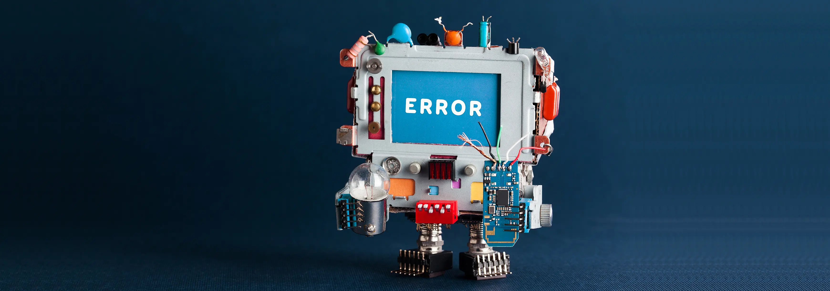 Toy robot computer with light bulb and defective circuit on dark blue background, with a head showing the text message Error on blue screen.